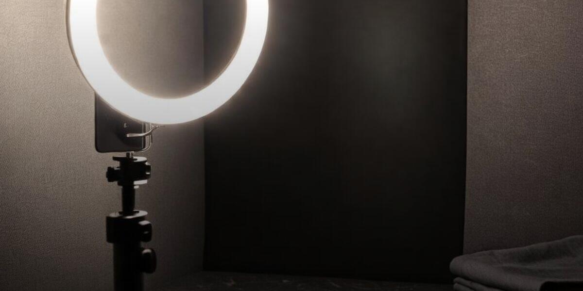 A tidy home-studio corner with a ring light, a phone tripod, and a folded fabric backdrop